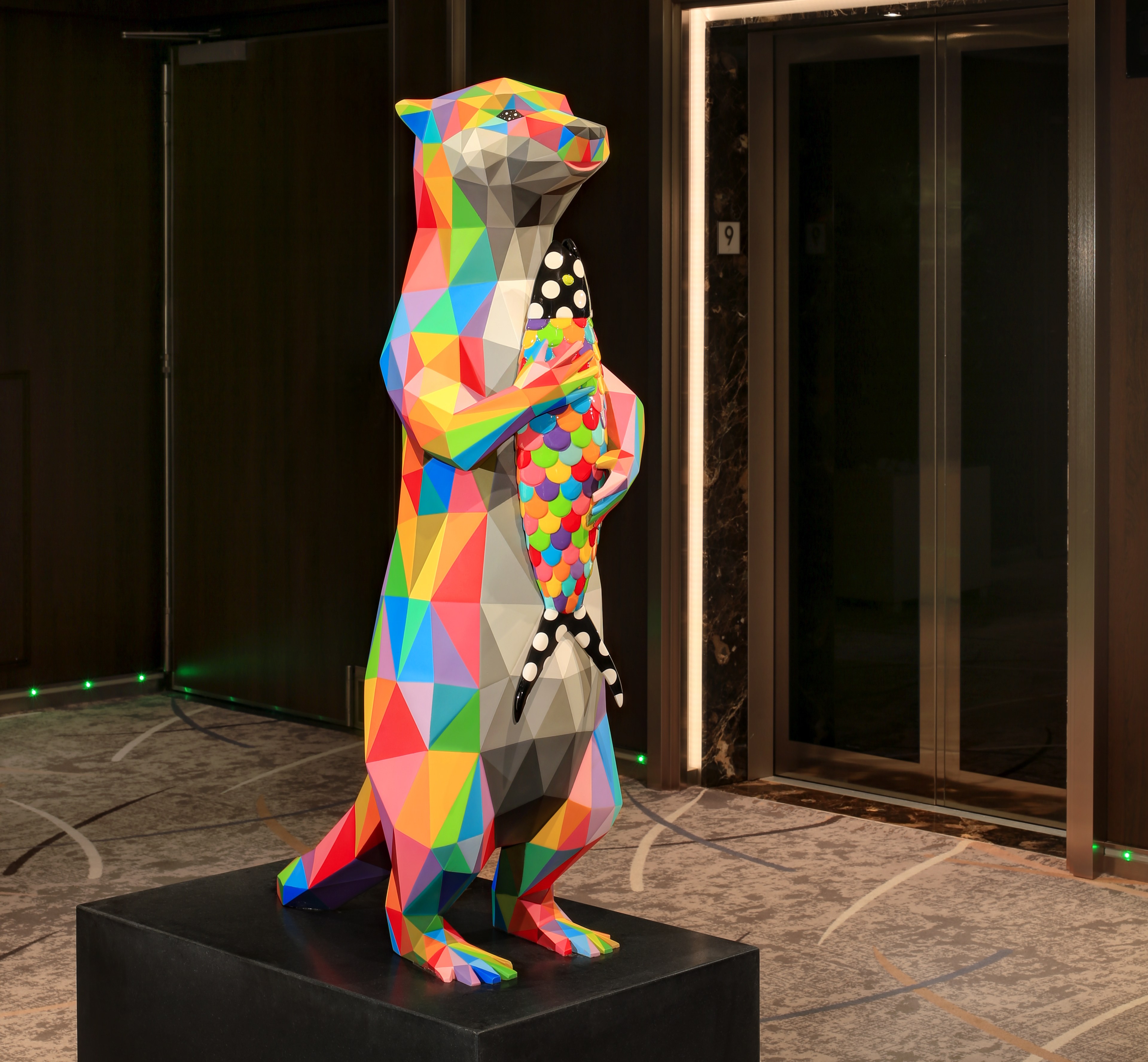 Polygonal art illustration of a multi-colored otter holding a fish.