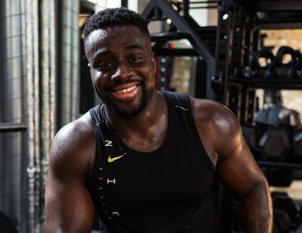 Will Duru, a personal trainer, strength and conditioning coach, and former footballer, smiling in a gym.