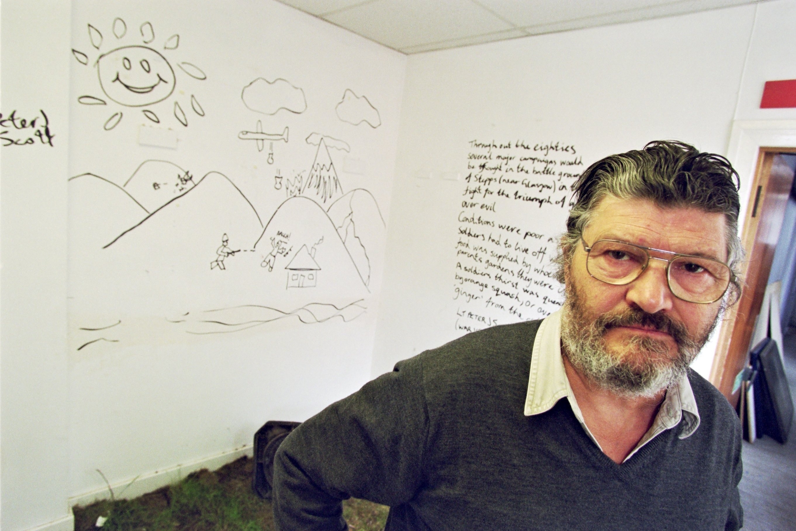 David Harding, lecturer in Environmental Art and Sculpture at Glasgow School of Art, in a room with writing and drawings on the walls.