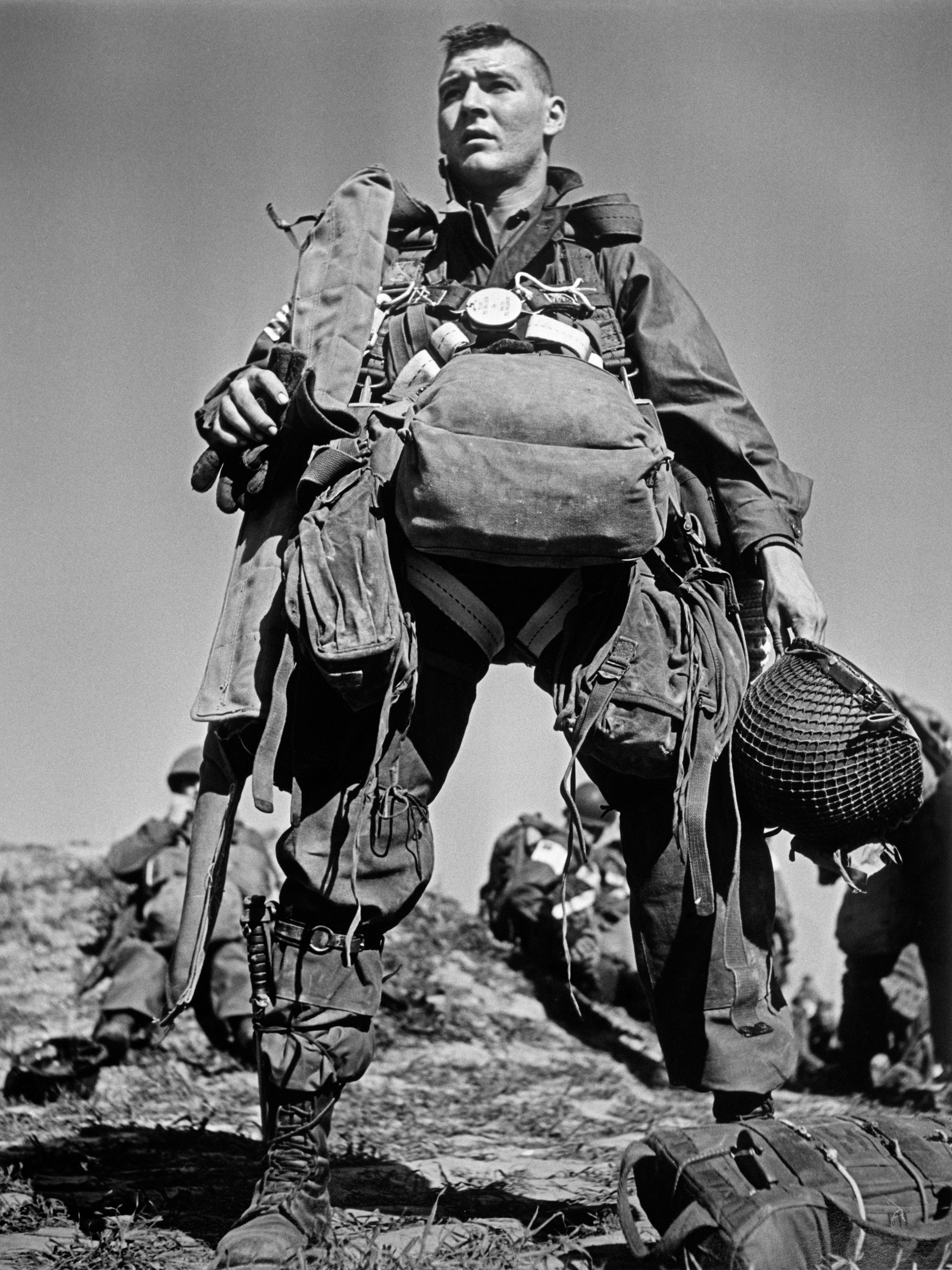 An American parachutist, heavily equipped with gear, preparing to jump across the Rhine River in 1945.