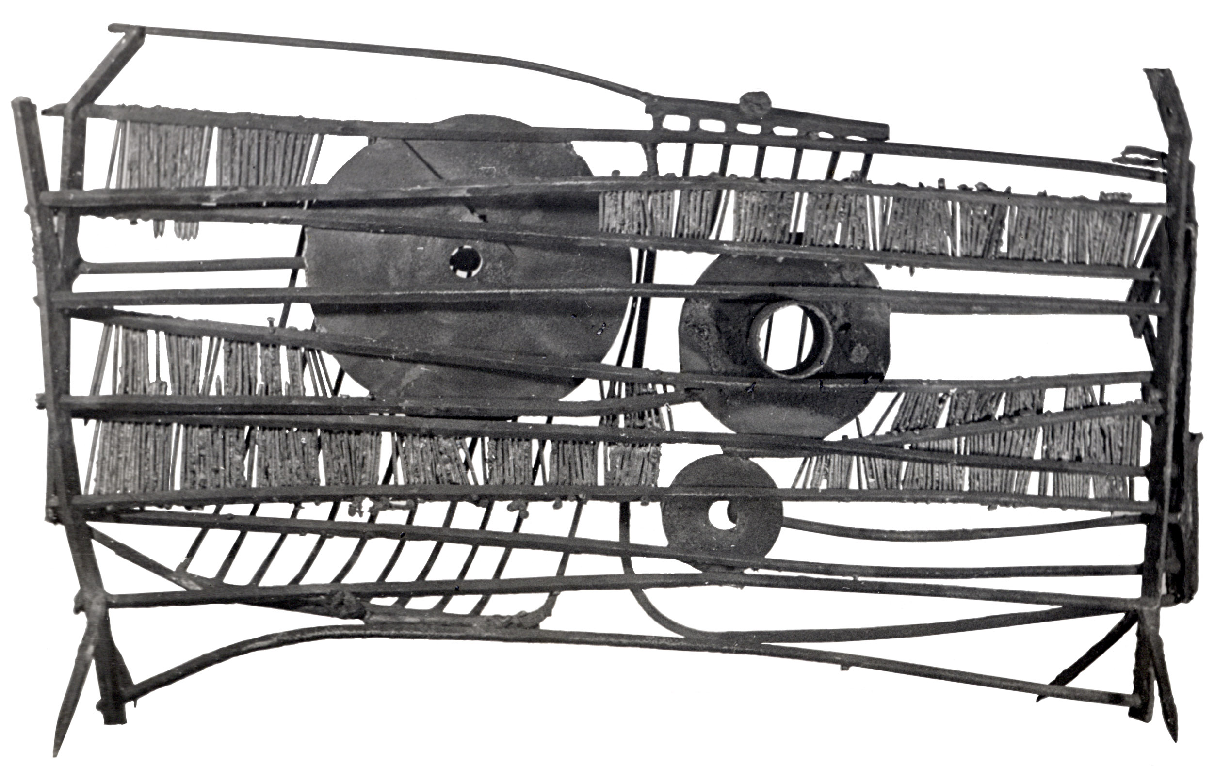 Photograph of a Fenwick Lawson sculpture depicting an abstract metal cage with various sized circular elements within.