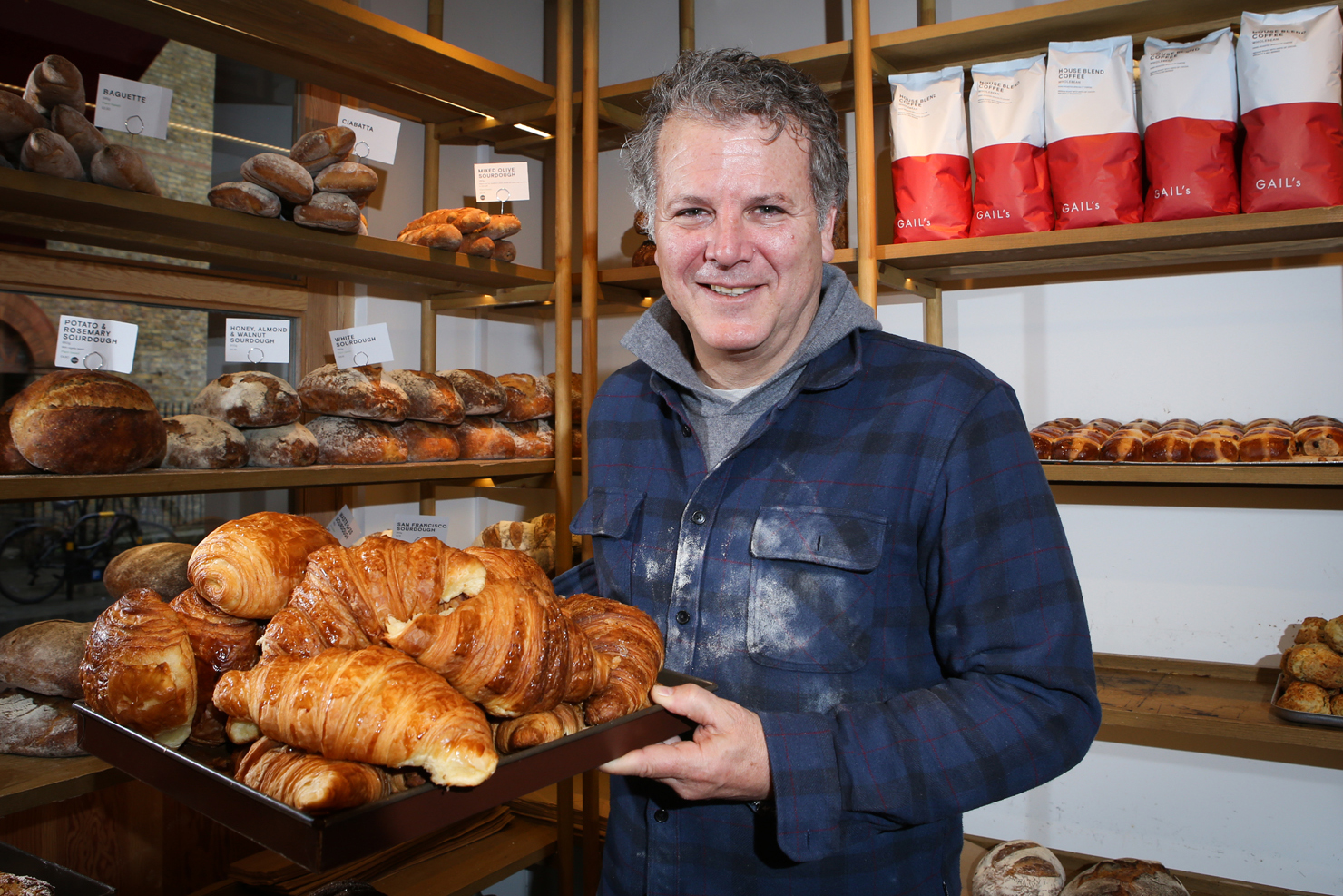 Tom Molnar, founder of Gail's bakery, holding a tray of croissants in his bakery.
