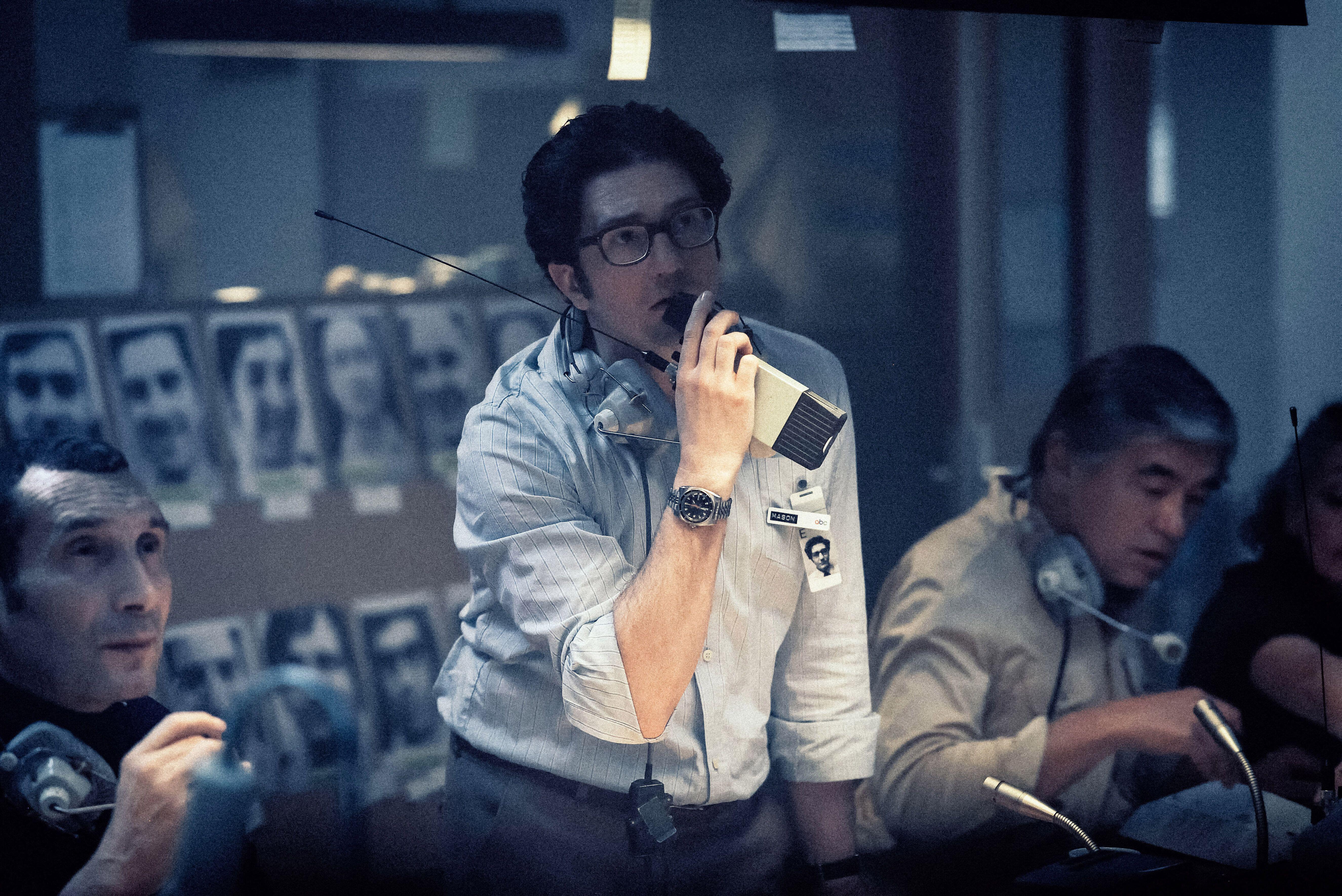 John Magaro as a man with a headset talking into a handheld radio in a still from the film about the 1972 Munich Olympic Games terror attack.