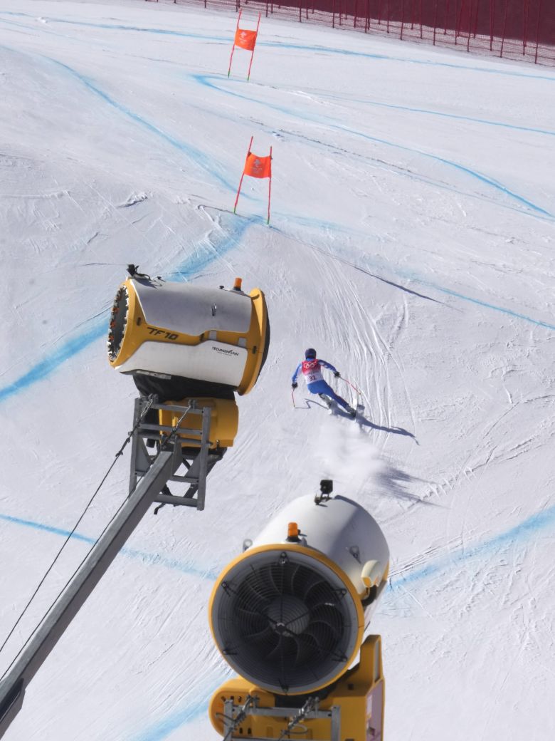 French skier Alexis Pinturault races past snow-making machines during a downhill training run at the 2022 Beijing Olympics.