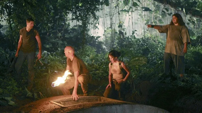 Hurley points a finger at Jack while Locke and Kate kneel down on the hatch hidden in the jungle in "Lost"