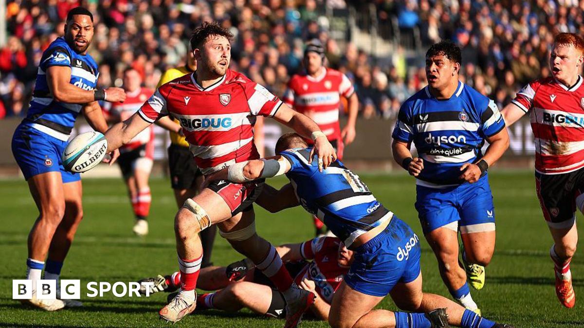 Gloucester's Will Trenholm is tackled during the Prem Rugby Cup match between Bath Rugby and Gloucester Rugby as players from both sides watch on