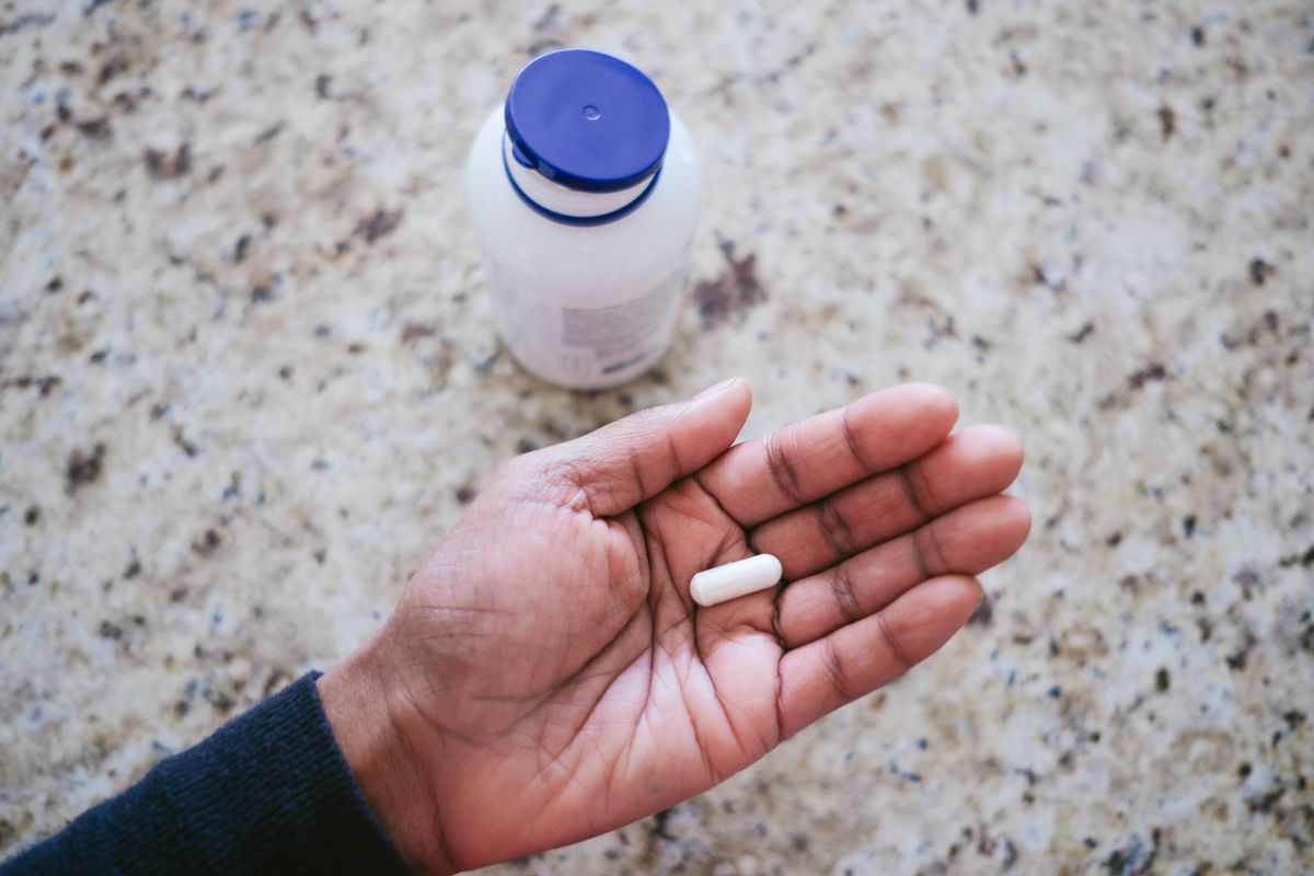 High angle view of unrecognizable black woman holding nutritional supplement in palm of her hand