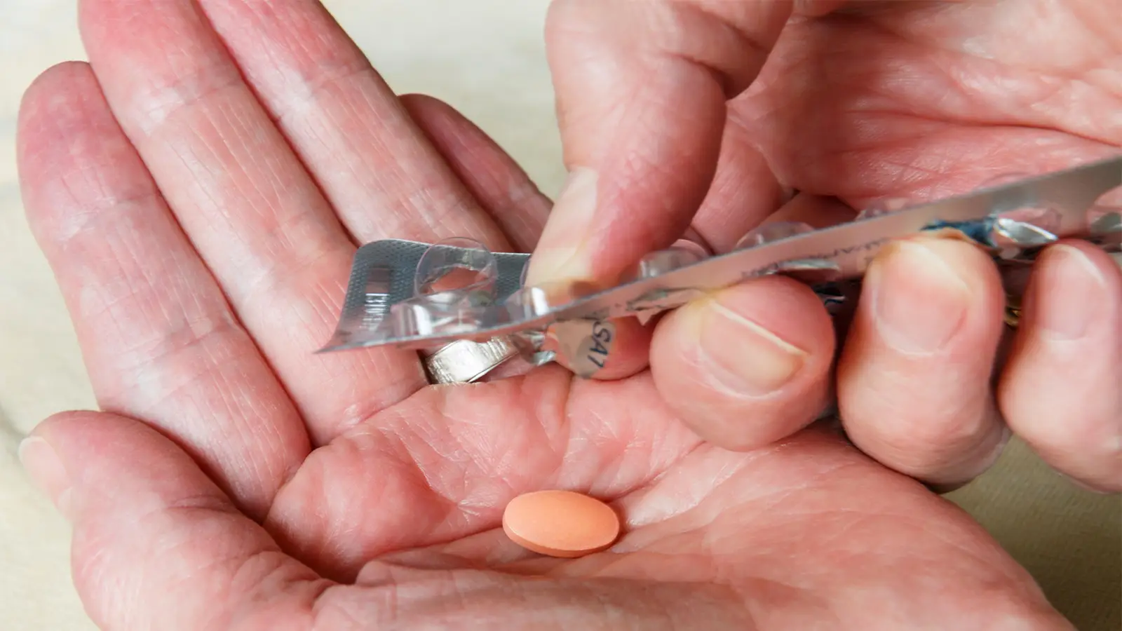 A photo of a man pushing a statin pill from its blisterpack.