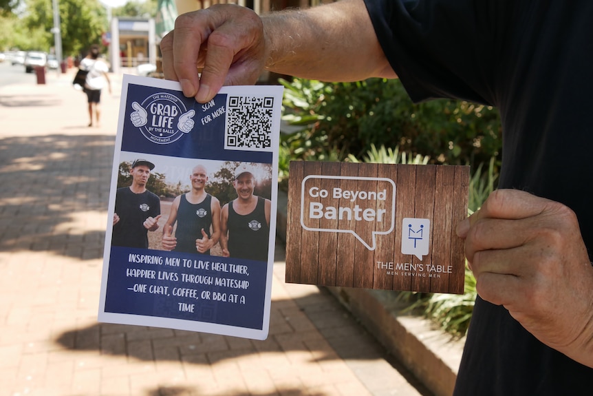 A person's hand holding two pamphlets 