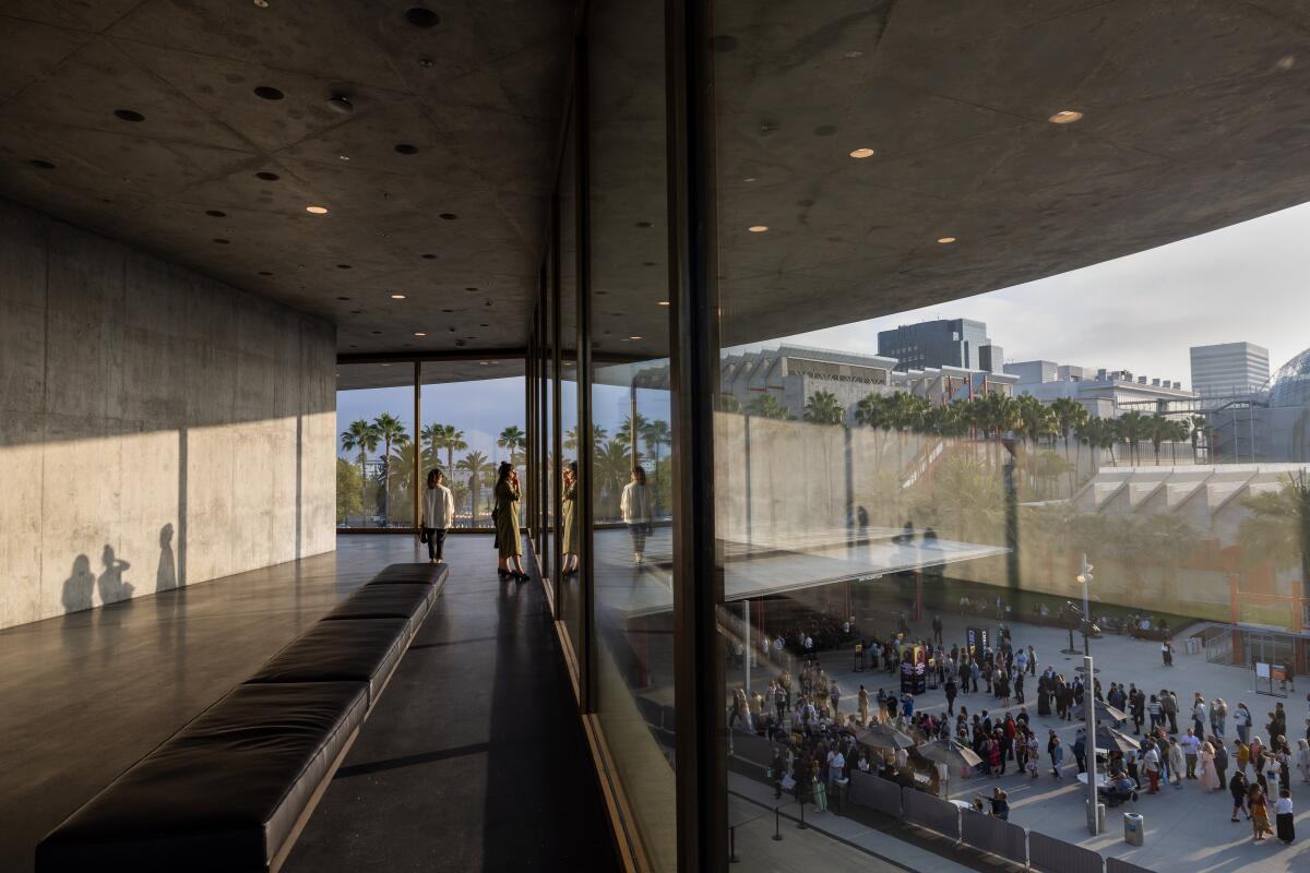 Guests look out the window of the Geffen Galleries upon a crowd below.