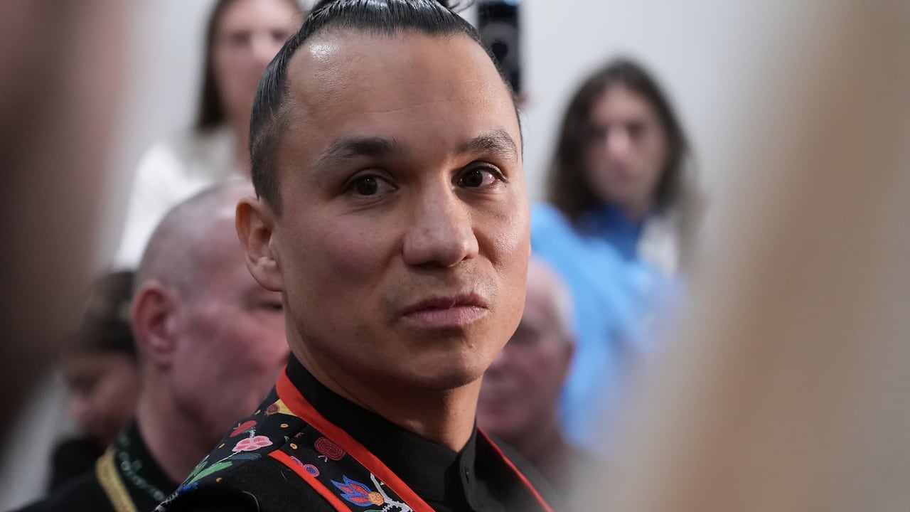 A man with a bun stares into the camera.