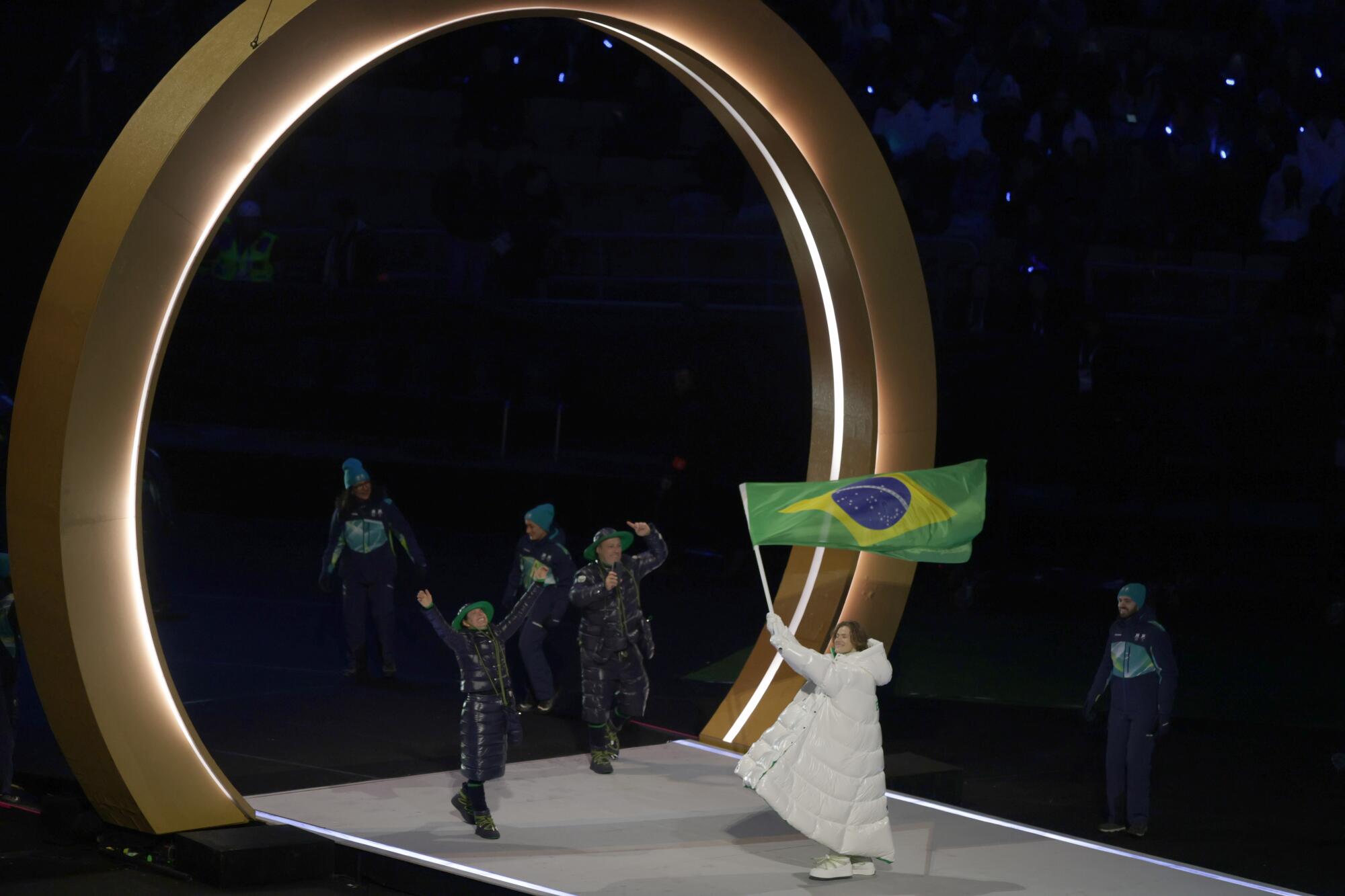 Lucas Pinheiro waves Brazil's flag while leading his teammates during the opening ceremony ofthe 2026 Winter Olympics.