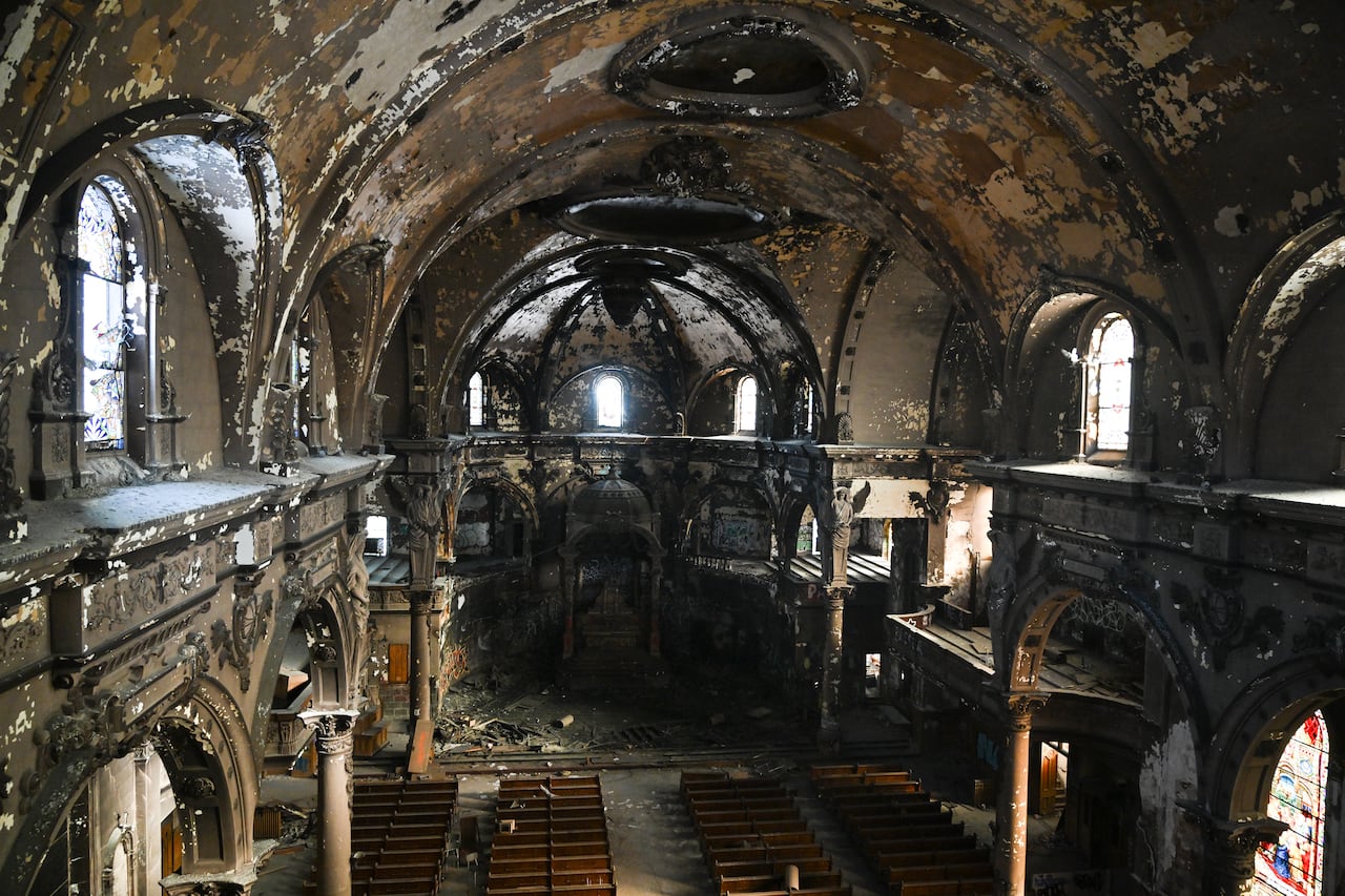 Broken pews, graffiti and debris are seen inside in a church. 