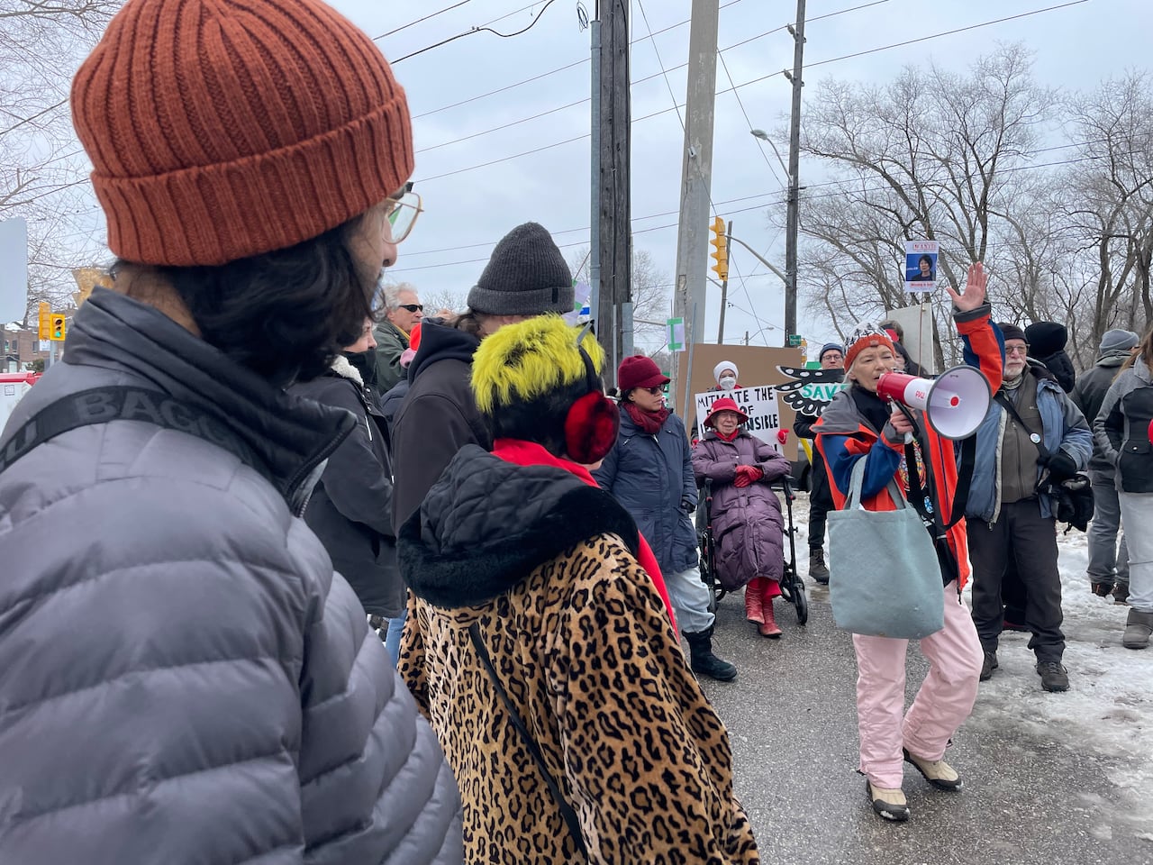 People holding signs and speaker at rally