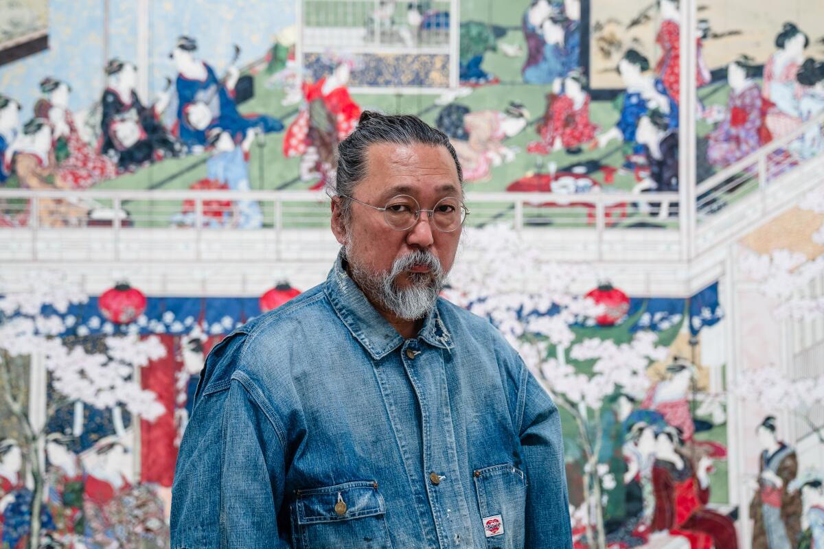 Takashi Murakami stands in front of a Japanese canvas.