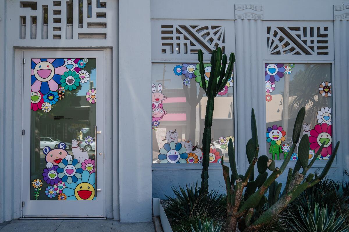 The entrance to a store with stickers on windows of colorful flowers with faces.