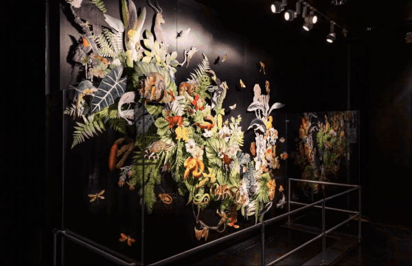 A gif of different angles of a colorful wall installation of foliage and butterflies against a black background