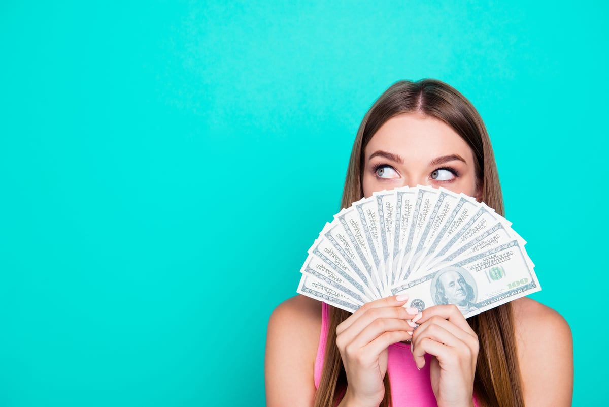 A person look out above a fanned stack of money.