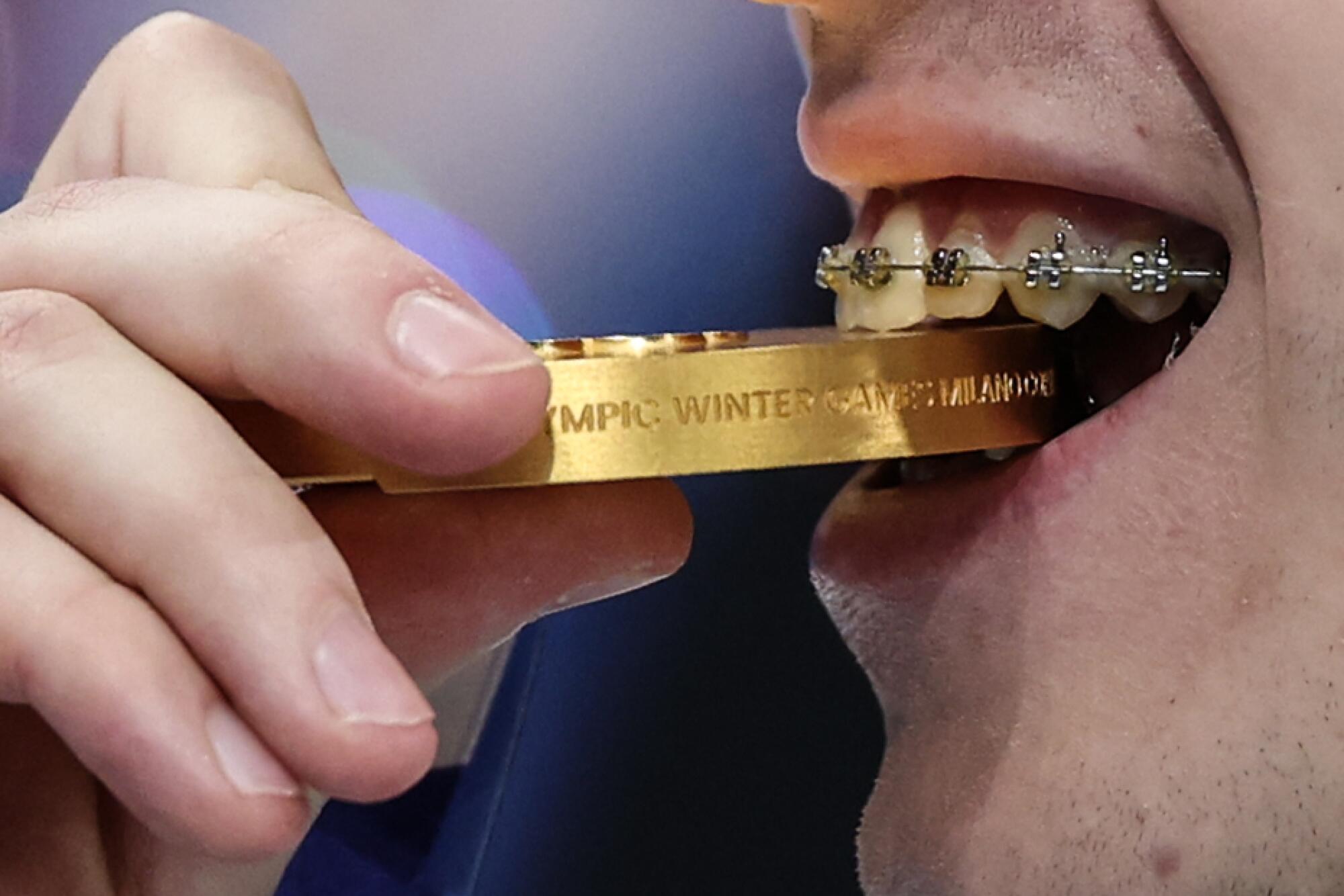 Mikhail Shaidorov shows his metal as he takes a bite of the Gold Medal he won in the Men’s Single Skating Final.