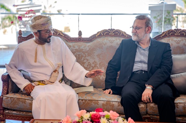 In this photo released by Iran's Supreme National Security Council office, Secretary of the Supreme National Security Council Ali Larijani, right, listens to Omani Foreign Minister Badr al-Busaidi during their meeting in Muscat, Oman, Tuesday, Feb. 10, 2026. (Erfan Kouchari/Iran's Supreme National Security Council Office via AP)
