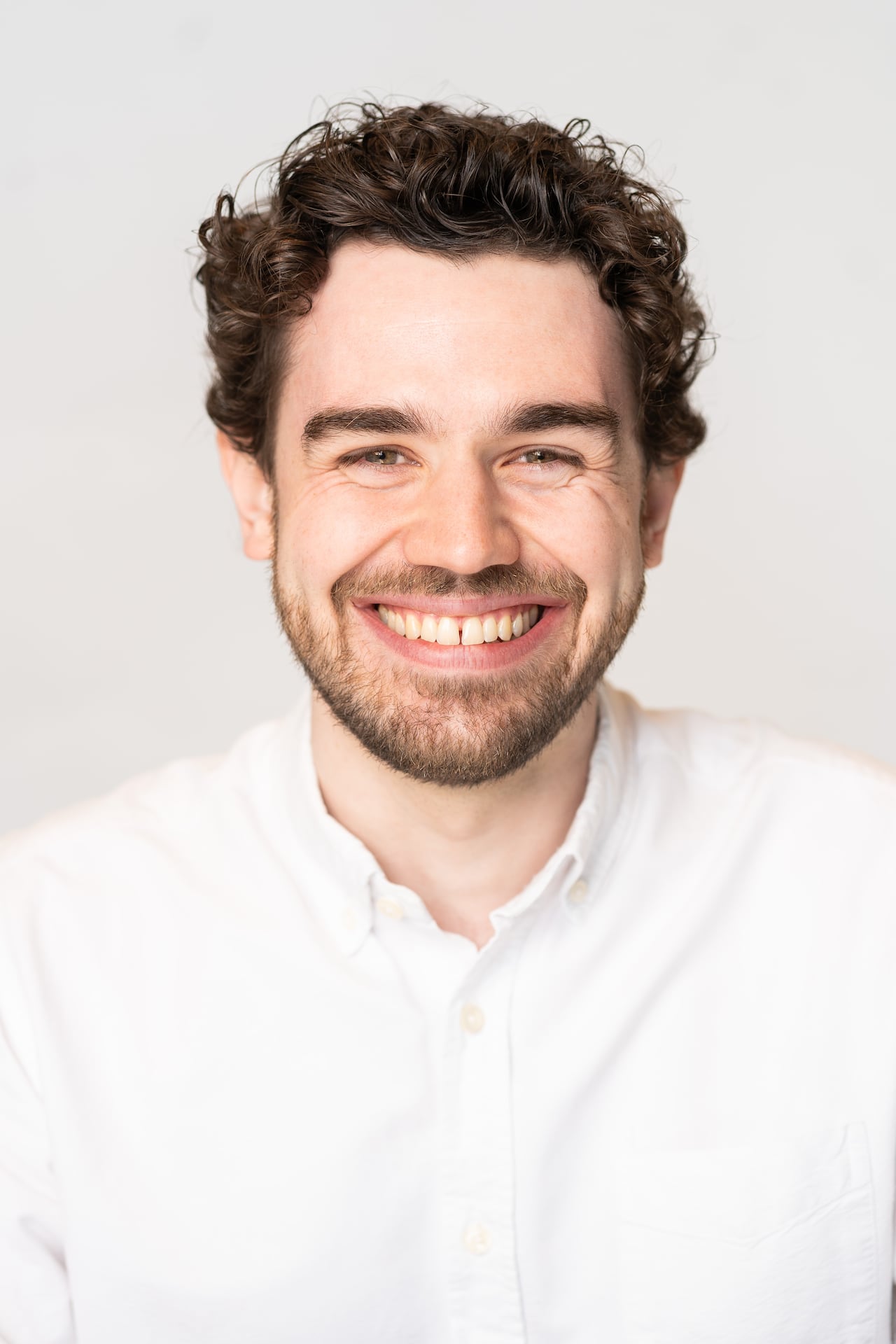 headshot of a man in white top.