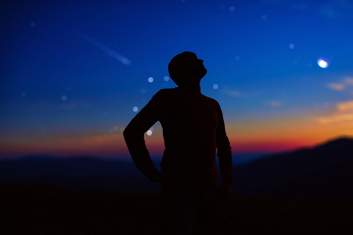 Person looking up at stars and planets in the night sky, stargazing. Credit: M-Gucci / Getty Images