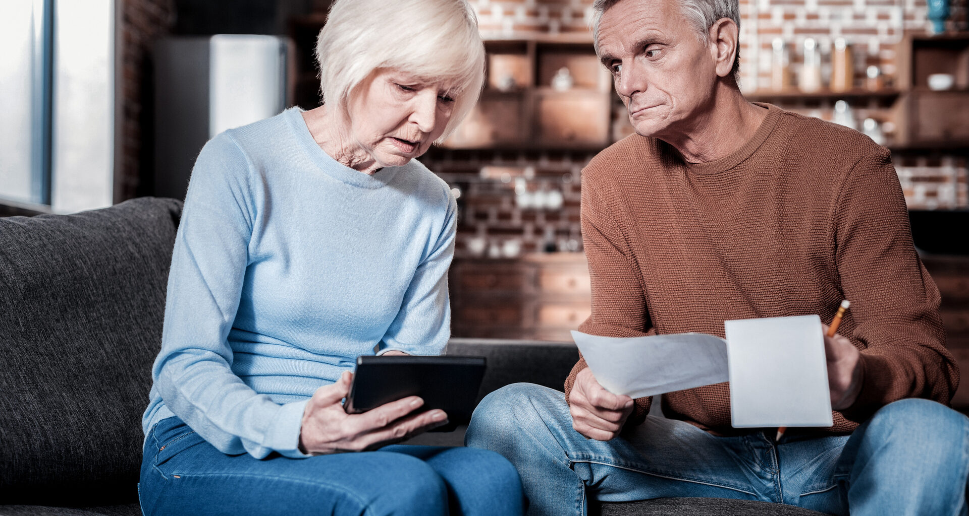 An upset couple sitting down looking at papers.