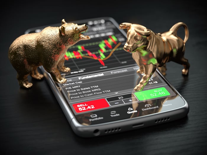 Bull and buy statues trading stocks on phone.