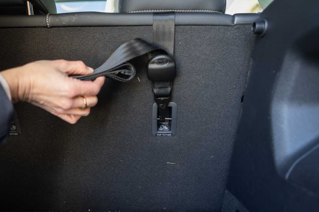 This image shows the tether of a front-facing car seat attached to the vehicle's back seat anchor point.