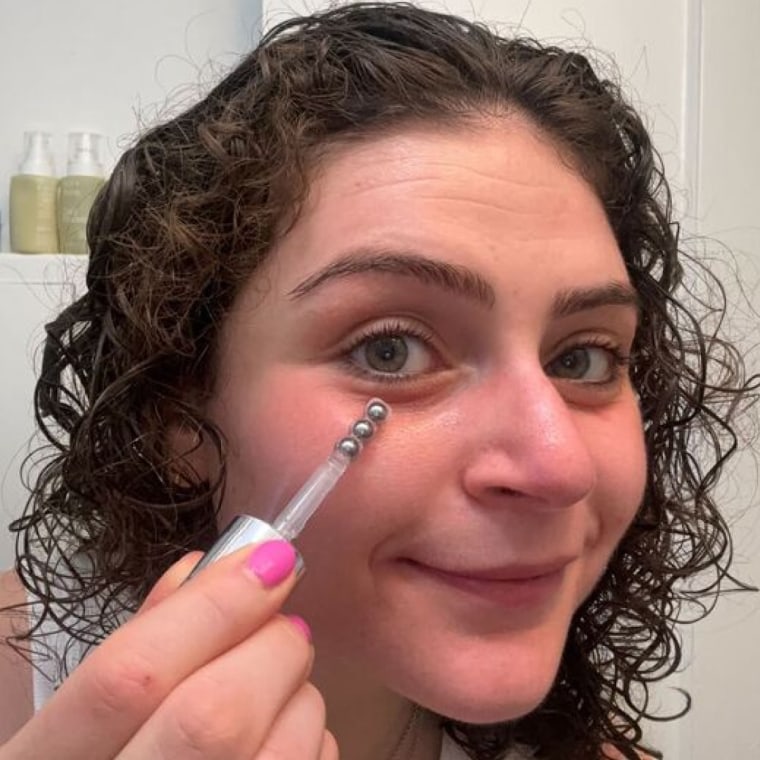 Woman applying eye cream applicator to her under eyes