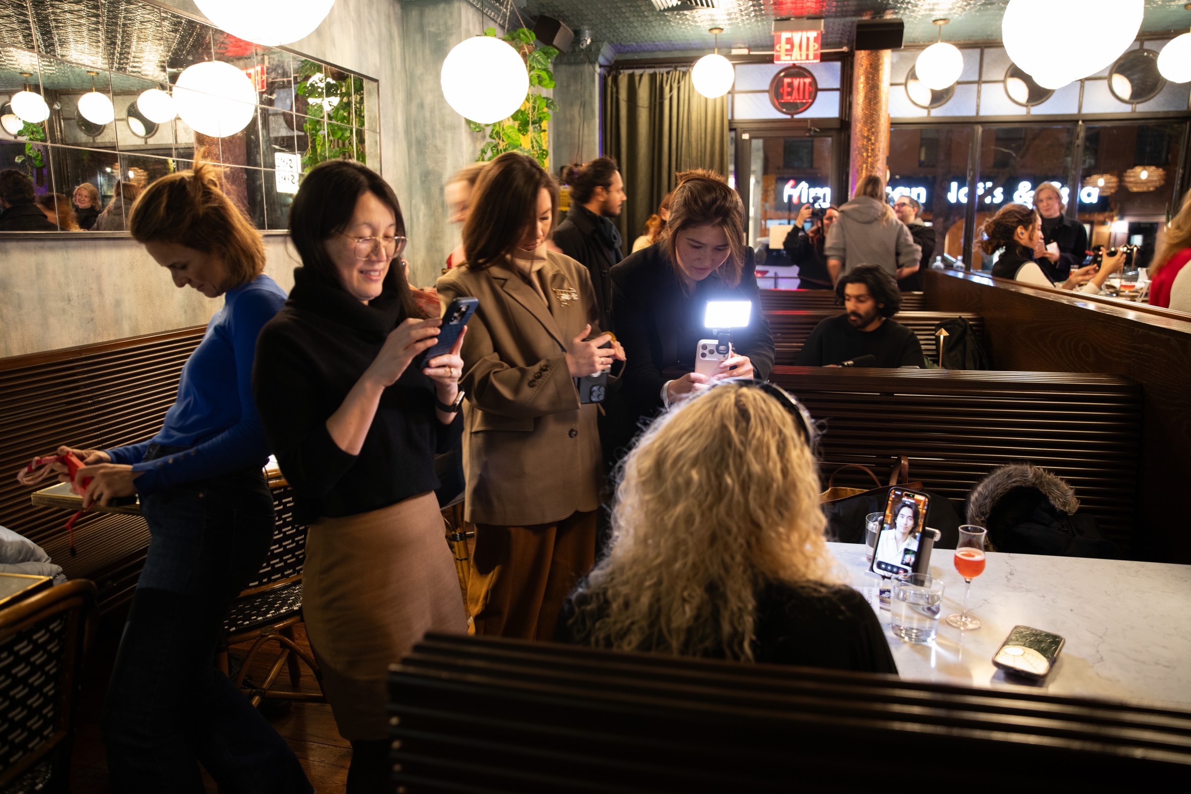 Reporters in a lively cafe taking photos of a woman on a date with an AI companion. 