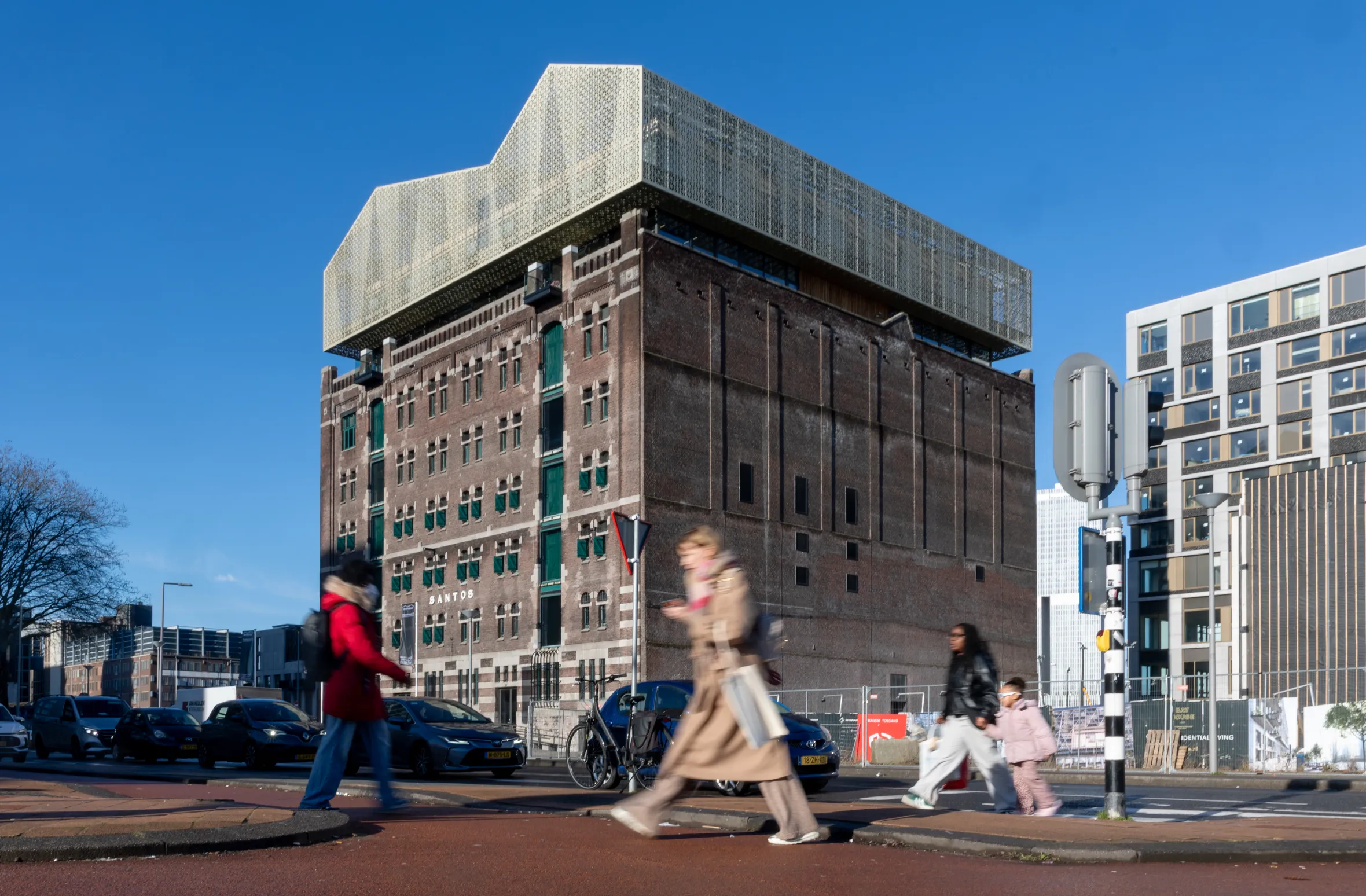 A photo of the Nederlands Fotomuseum in Rotterdam, which is housed in a large brick building with a modern, geometric addition on top, against a clear blue sky.