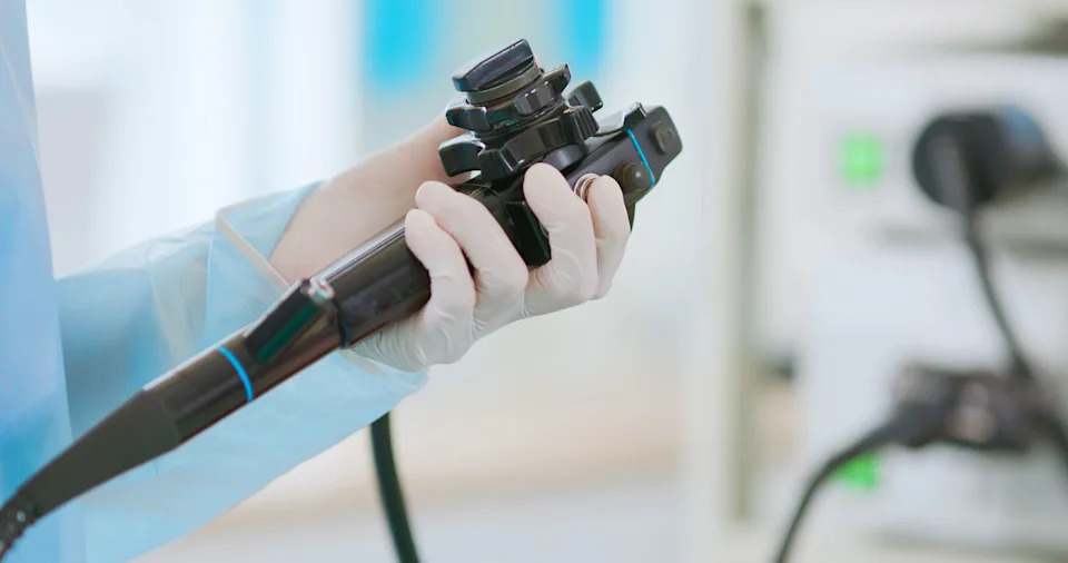 A health-care provider holds a tool used for colonoscopies, checking a patient for colorectal cancer.