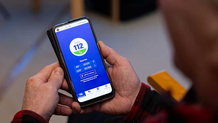 Person's hands holding a smartphone that is showing the 112 emergency services app's blue screen.