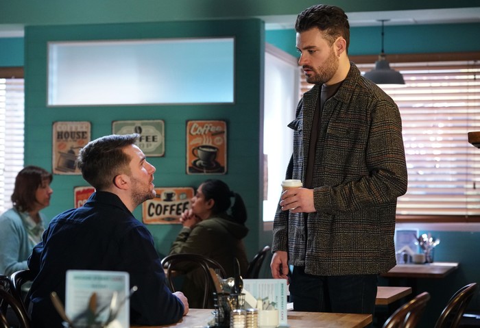 550914,TITLE:Eastenders Johnny stands over Callum, holding a coffee cup, in a scene set in the EastEnders cafe