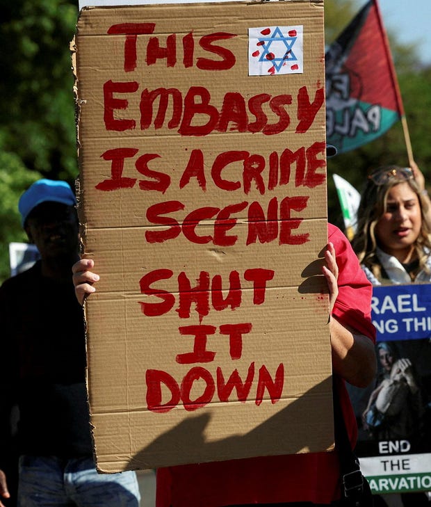 Activists hold placards and shout slogans outside Israel's embassy as they protest the detention of members of a Gaza-bound aid flotilla, in Pretoria, South Africa, October 3, 2025.