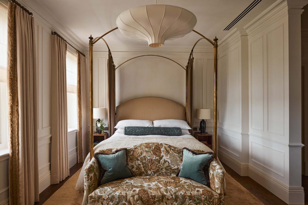 Stylishly furnished bedroom featuring a four-poster bed and decorative couch.