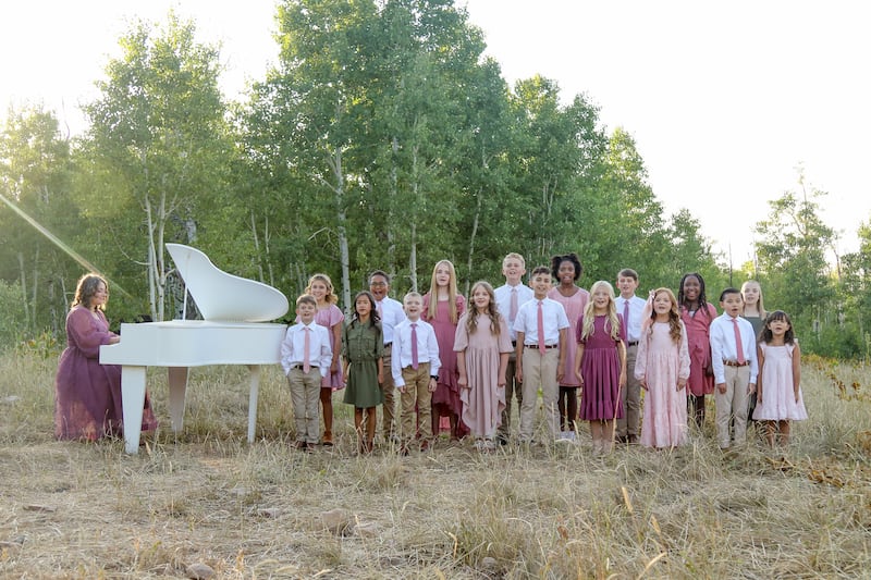 Angie Killian, composer of "Anytime, anywhere," plays the piano while children sing during the music video shoot for the extended version of "Anytime, anywhere," in Payson Canyon, 2025.