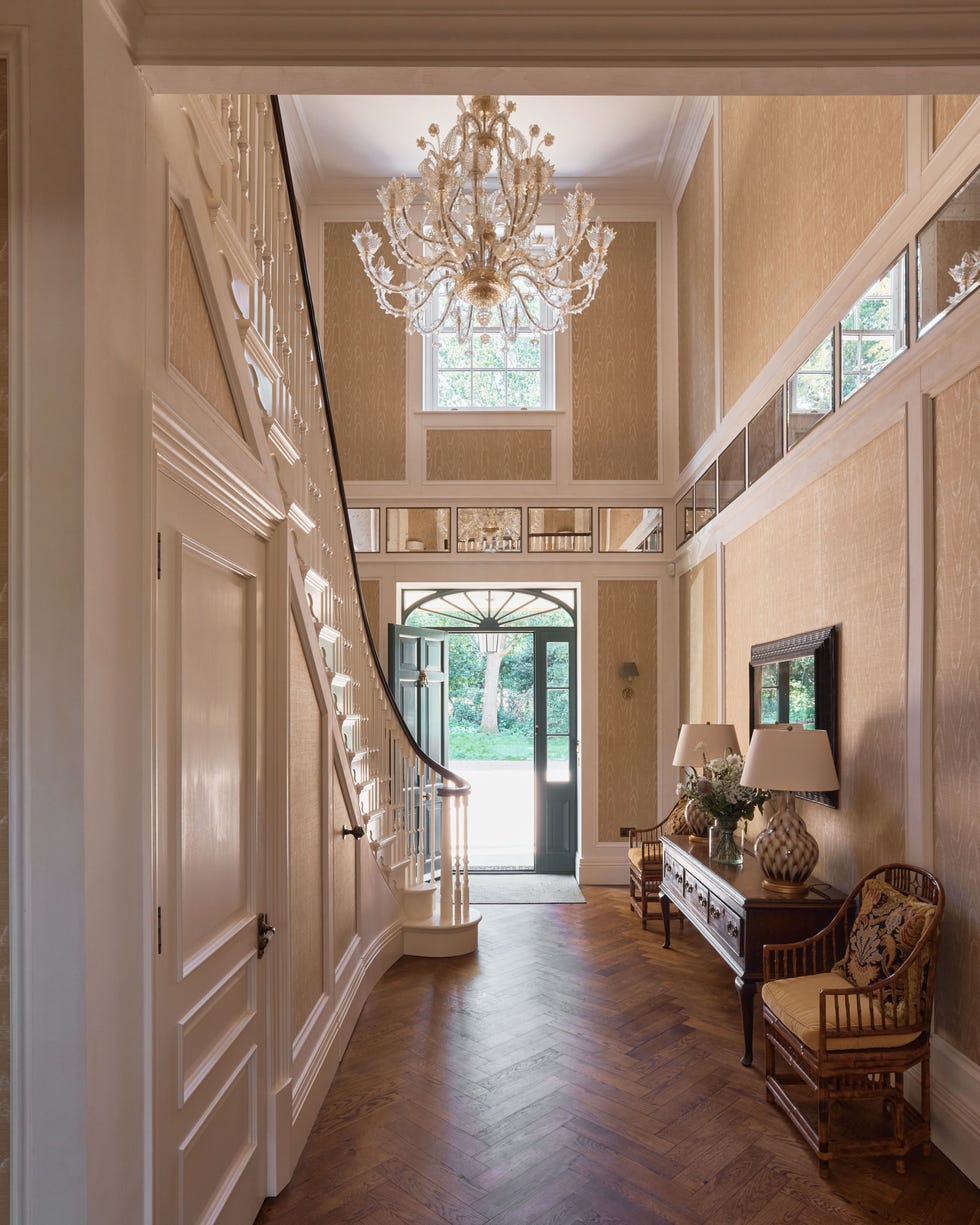 Entryway with a staircase and chandelier, showcasing decor and natural light.