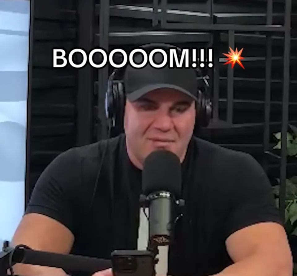 A.J., wearing a black baseball cap and black t-shirt, talking into a mic and wearing over-head headphones.