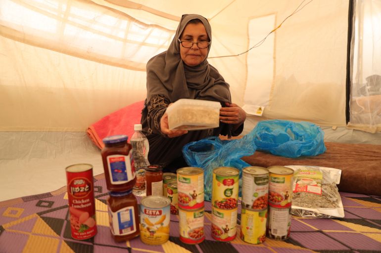 A woman sorts through cans from an aid package