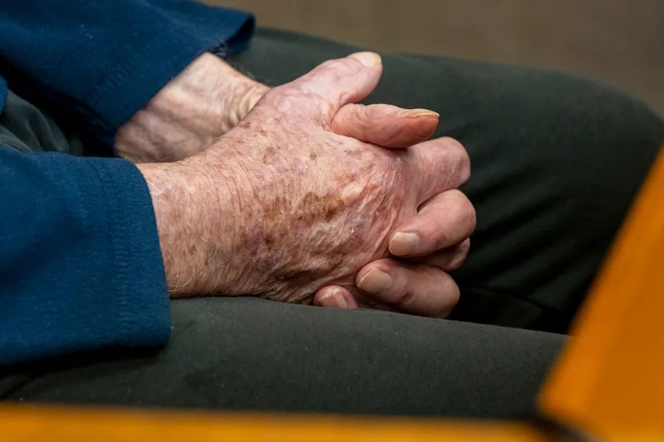 A nursing home resident clasps his hands. Getty
