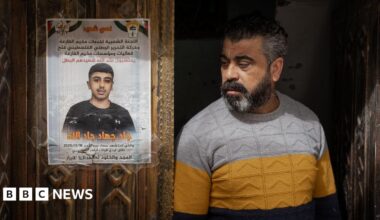 Jad's father stands next to a memorial poster of his son, taped to the family's carved wooden front door in al-Far'a refugee camp, in the occupied West Bank