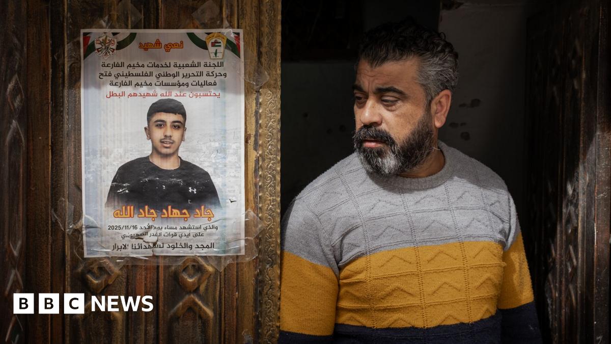 Jad's father stands next to a memorial poster of his son, taped to the family's carved wooden front door in al-Far'a refugee camp, in the occupied West Bank