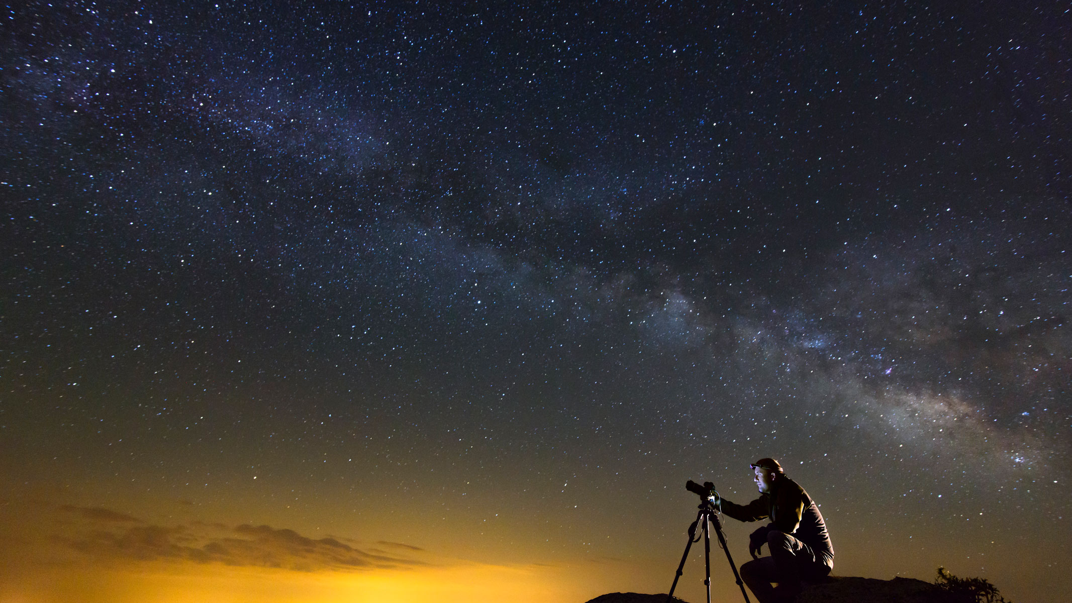 A person using a camera to take photos of the night sky.