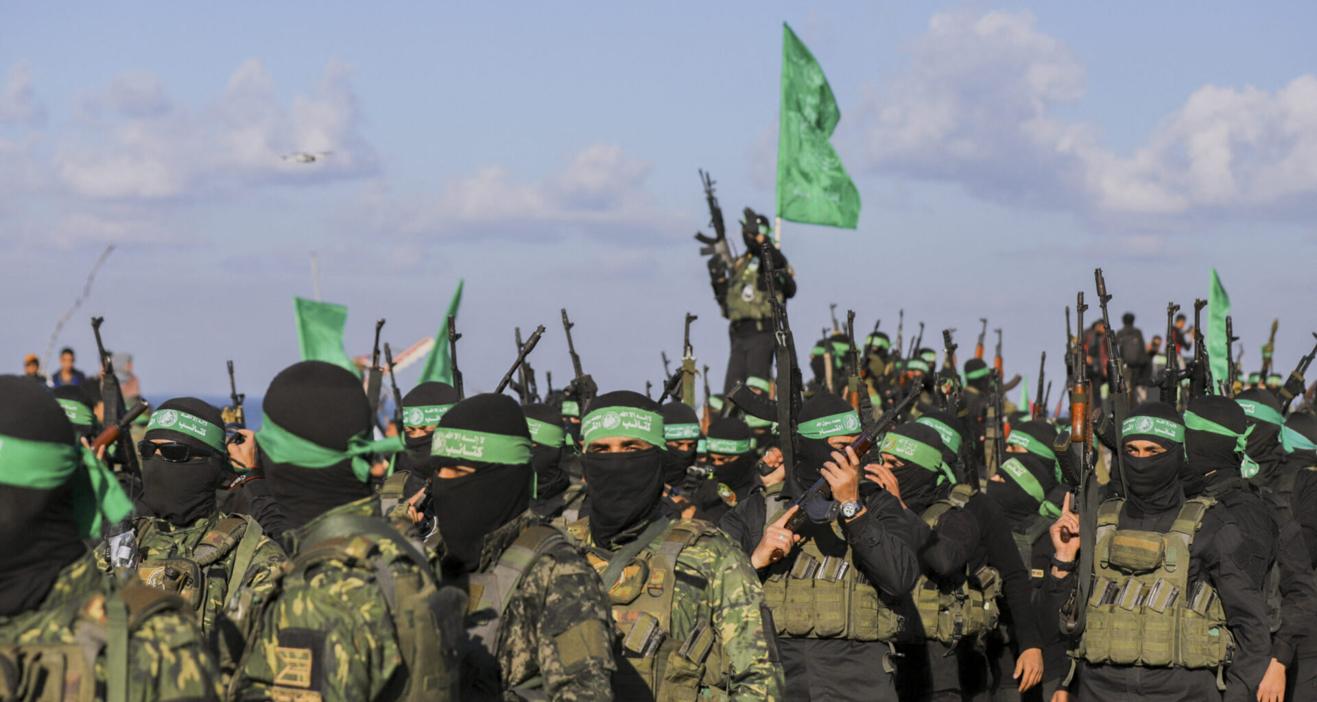 Palestinian militant group Hamas fighters secure an area before handing over an Israeli-American hostage to a Red Cross team in Gaza City on February 1, 2025, as part of the fourth hostage-prisoner exchange. Ranks of Hamas fighters formed up on Gaza's beachfront on February 1 for the handover of an Israeli-American hostage Keith Siegel in a show of force against the dramatic backdrop of breaking waves. (Photo by Saeed Jaras / Middle East Images via AFP)