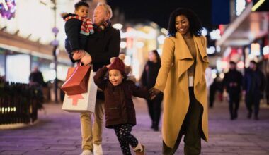 A front-view shot of a multi-ethnic family with two children walking down a city street on a cold December night.