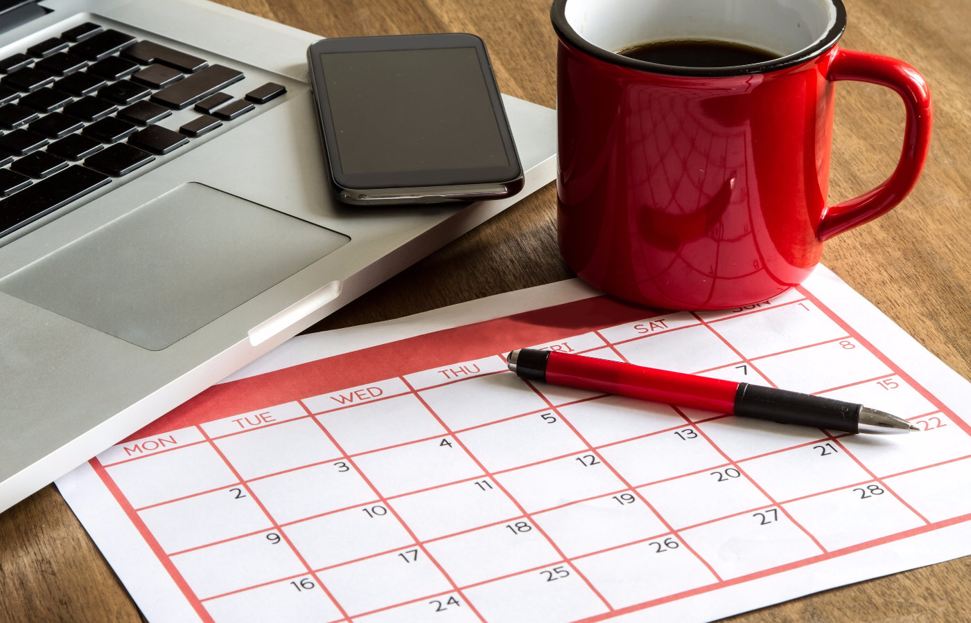 Calendar next to laptop and coffee cup