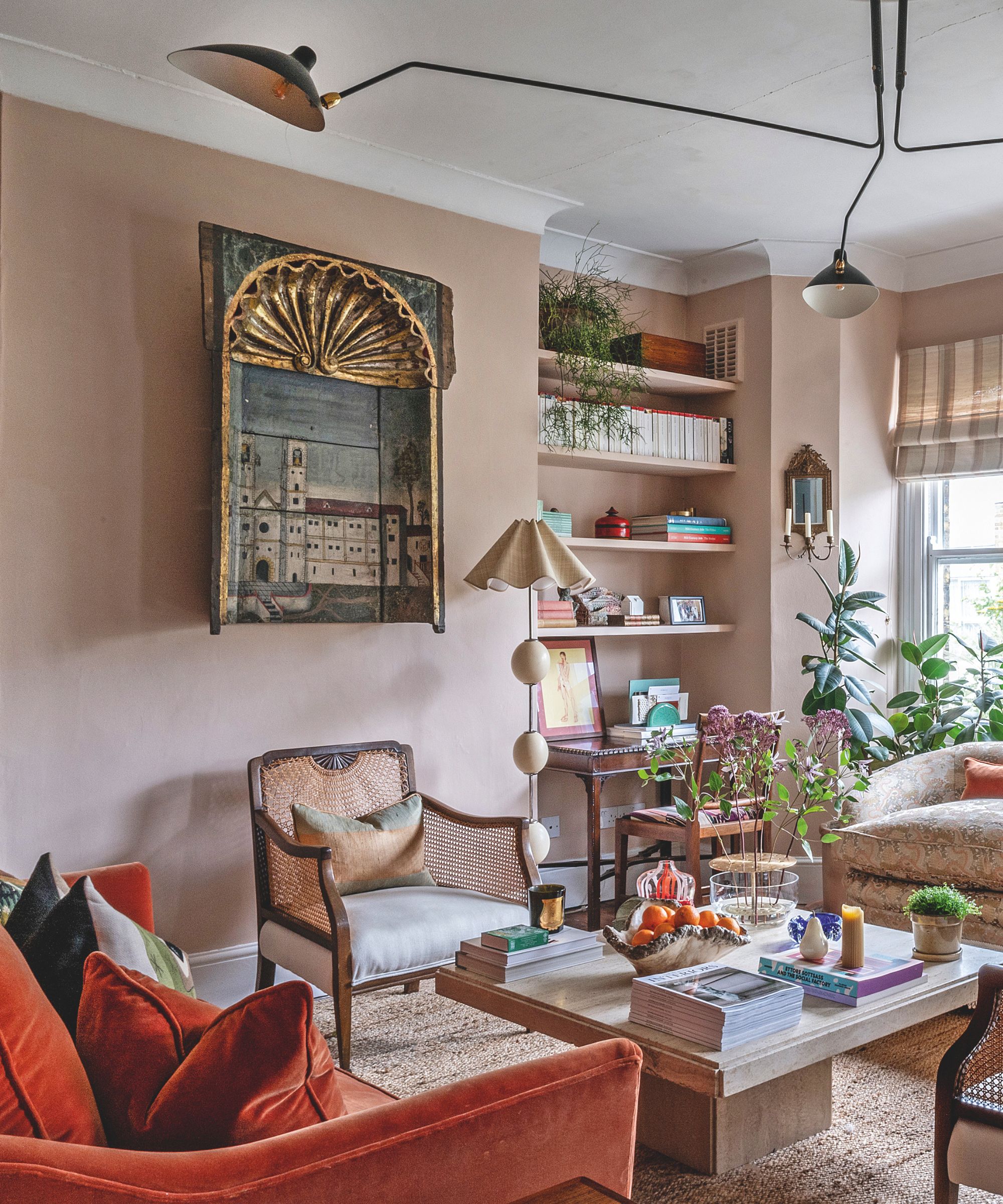A detailed view of a living room corner showing a vintage architectural painting of a church, a tiered floor lamp, and white floating shelves filled with books