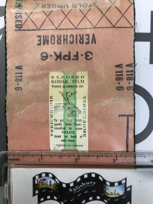 A vintage Kodak film envelope labeled “VERICHROME” and “EXPOSED KODAK FILM” lies upside down on a table, above a filmstrip bookmark with an image of Salisbury Cathedral in England.